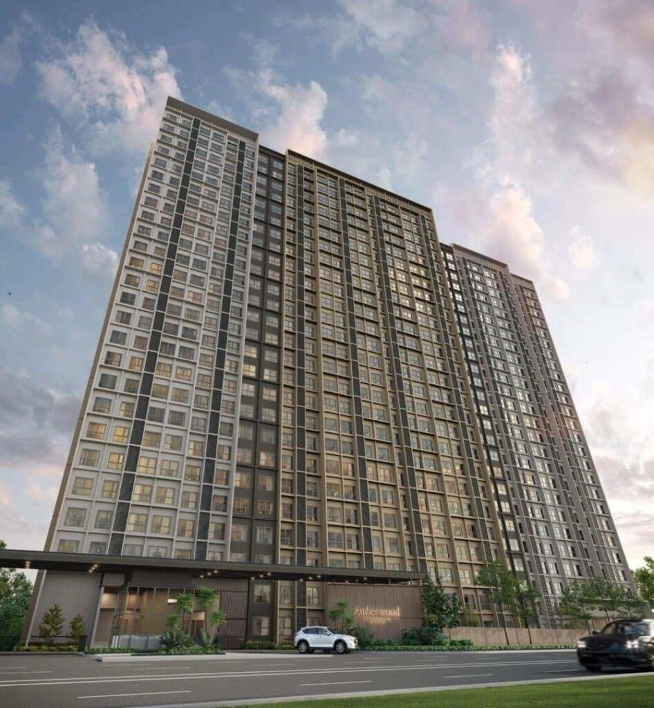 Amberwood Resort Residences 大楼外观效果图，展示两座约26层高的现代公寓大楼，底层设有入口大堂及景观绿化，前方为街道及停泊的白色轿车，背景为蓝天白云